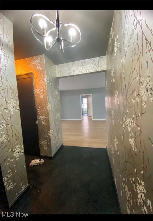 hall featuring wood-type flooring and an inviting chandelier