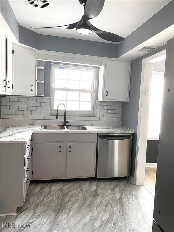 kitchen featuring decorative backsplash, stainless steel dishwasher, ceiling fan, sink, and white cabinets