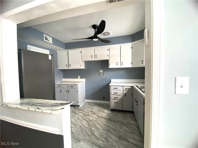 kitchen with stainless steel fridge, white cabinets, and ceiling fan