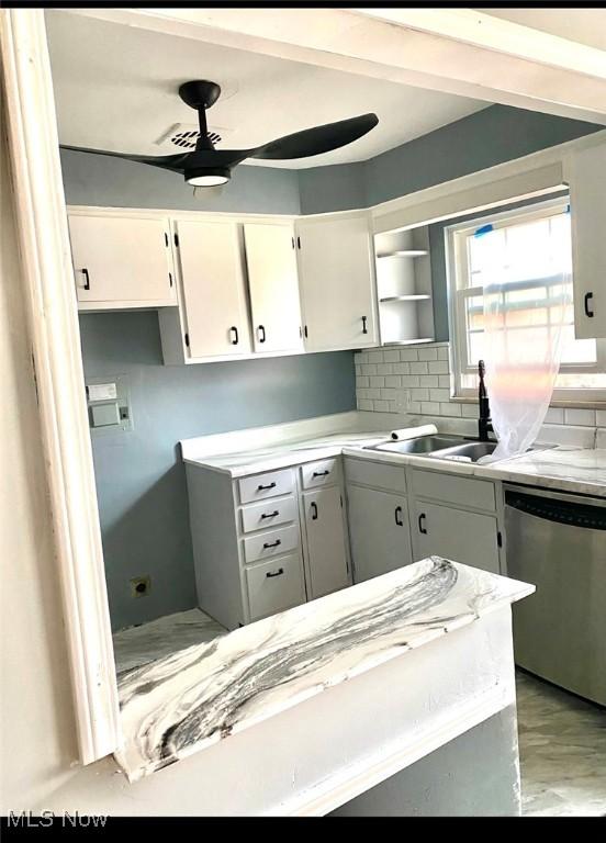 kitchen featuring dishwasher, sink, decorative backsplash, ceiling fan, and white cabinetry