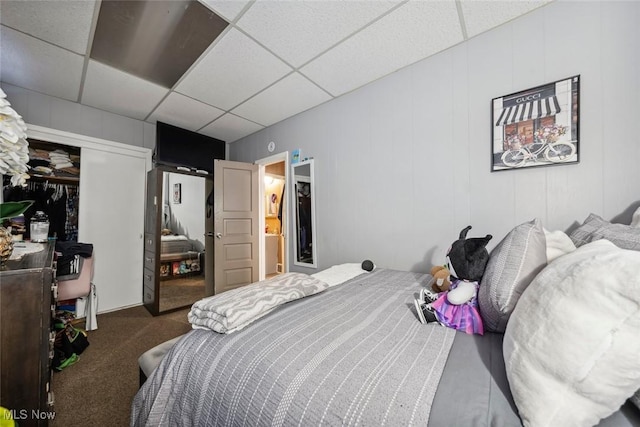 carpeted bedroom with a drop ceiling and a closet