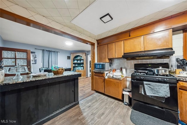 kitchen featuring light hardwood / wood-style floors, light stone countertops, black range with electric cooktop, and tasteful backsplash