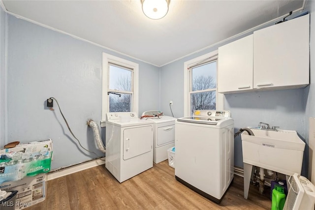 washroom with cabinets, light hardwood / wood-style flooring, a wealth of natural light, and washing machine and clothes dryer