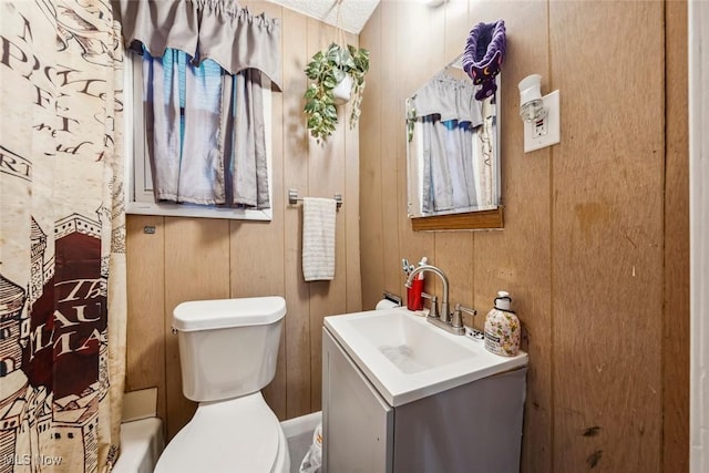 bathroom with wood walls, vanity, and toilet