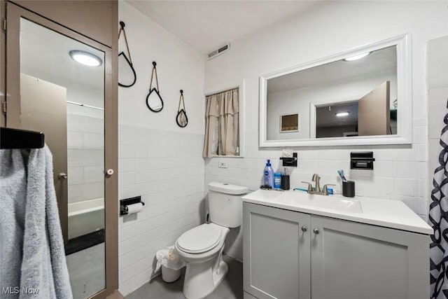 bathroom featuring vanity, tile walls, and toilet