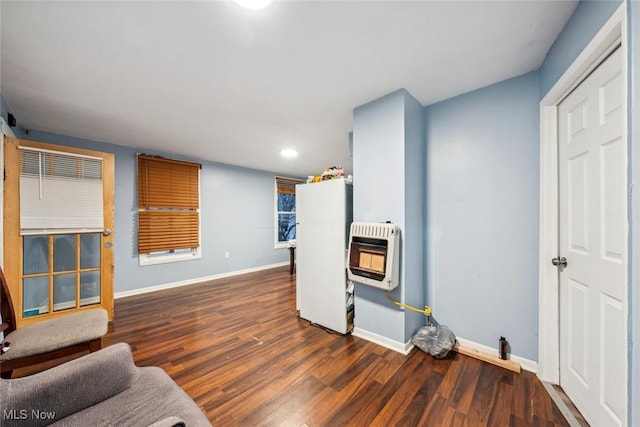 living room with heating unit and dark wood-type flooring