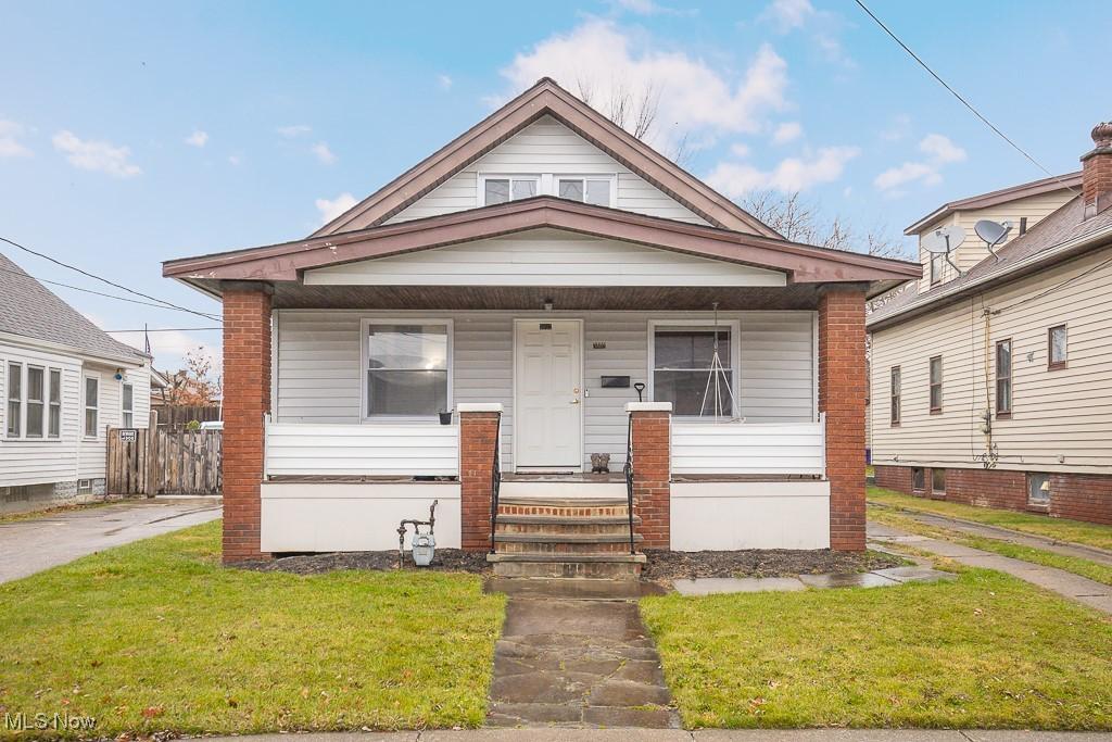 bungalow-style home featuring covered porch and a front lawn