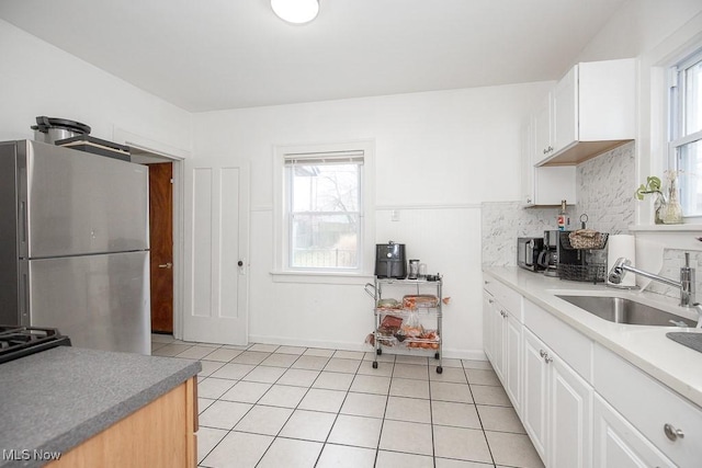 kitchen with white cabinets, sink, stainless steel refrigerator, and tasteful backsplash