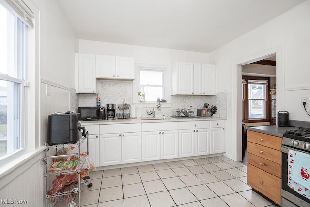 kitchen with white cabinets, decorative backsplash, and a healthy amount of sunlight