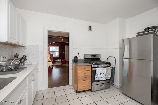 kitchen with backsplash, sink, light wood-type flooring, white cabinetry, and stainless steel appliances