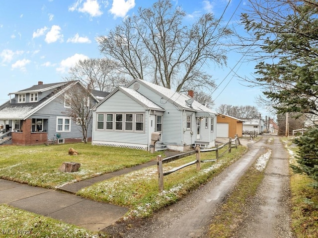 bungalow with a garage, an outdoor structure, and a front yard