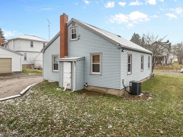 back of property with a yard and central AC