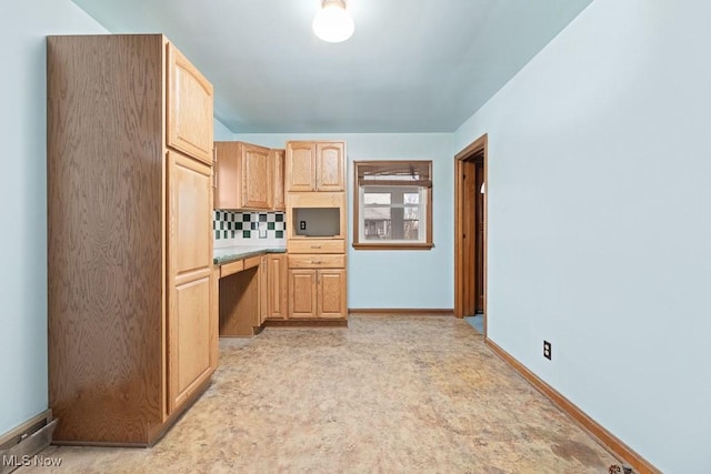 kitchen featuring light brown cabinets, built in desk, and backsplash