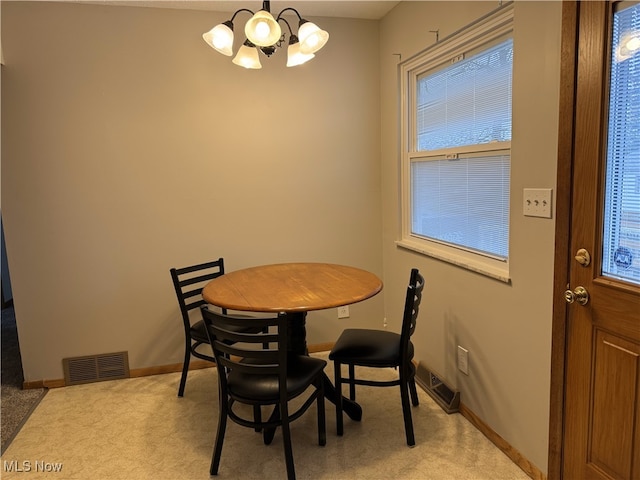 dining room with light colored carpet and a chandelier