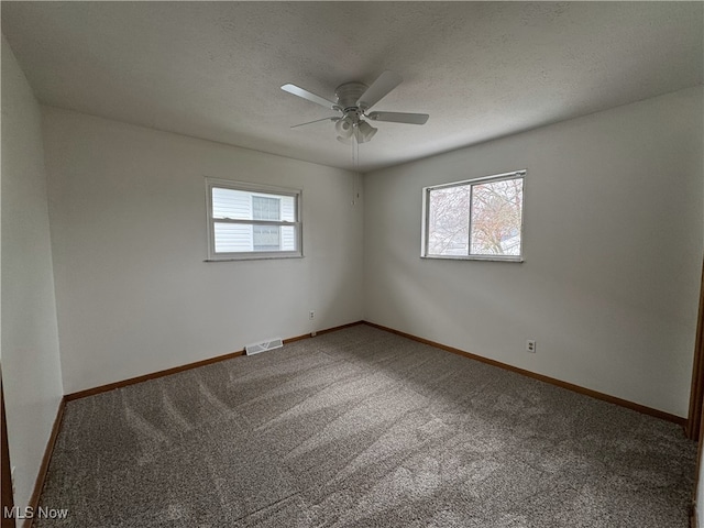 carpeted empty room with a textured ceiling, ceiling fan, and a healthy amount of sunlight