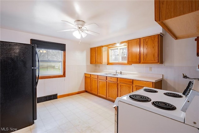 kitchen featuring electric range, black refrigerator, ceiling fan, and sink