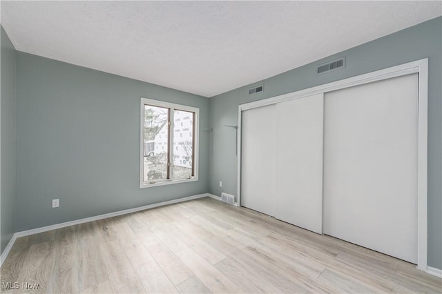 unfurnished bedroom with a closet, a textured ceiling, and light wood-type flooring