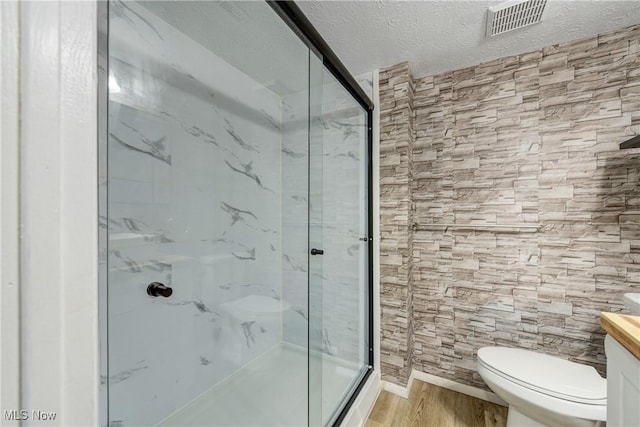 bathroom featuring vanity, a shower with door, hardwood / wood-style flooring, toilet, and a textured ceiling