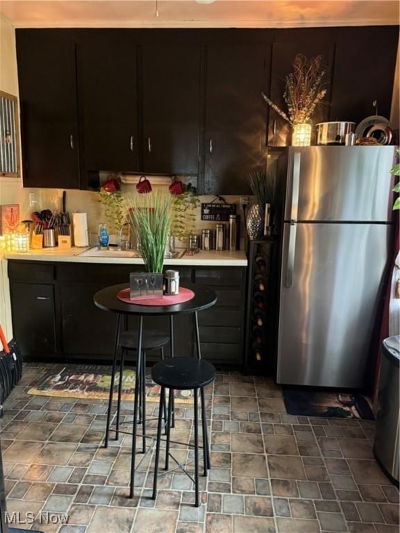 kitchen with decorative backsplash, stainless steel fridge, and sink