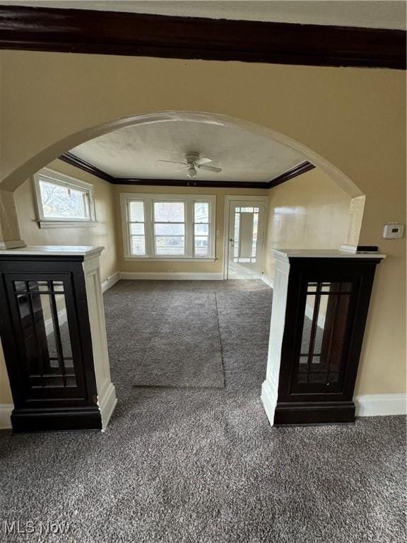 foyer entrance with dark colored carpet, plenty of natural light, ornamental molding, and ceiling fan