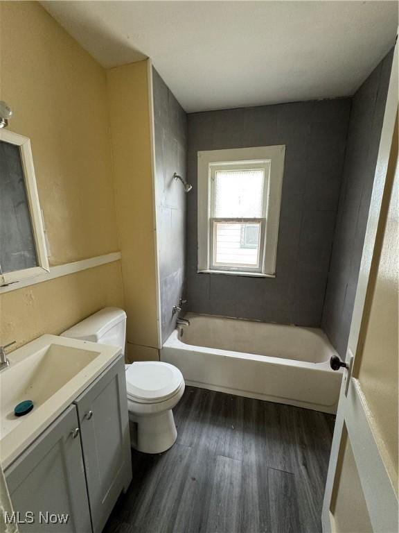 full bathroom featuring hardwood / wood-style flooring, vanity, toilet, and tiled shower / bath