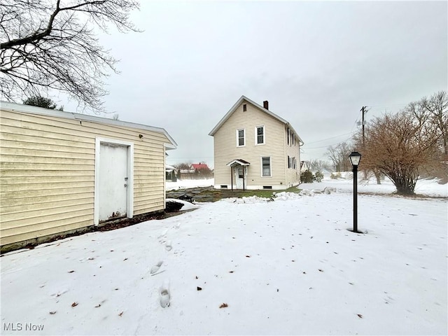 snow covered back of property with an outdoor structure
