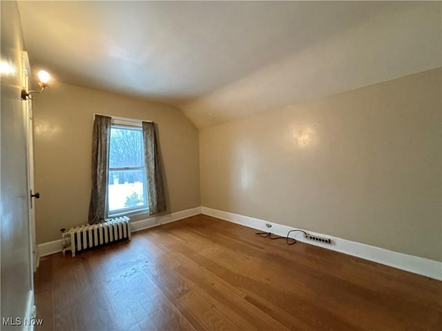 bonus room with hardwood / wood-style flooring, vaulted ceiling, and radiator