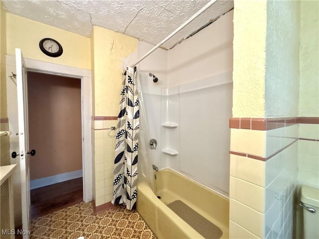 bathroom with shower / bath combination with curtain and a textured ceiling