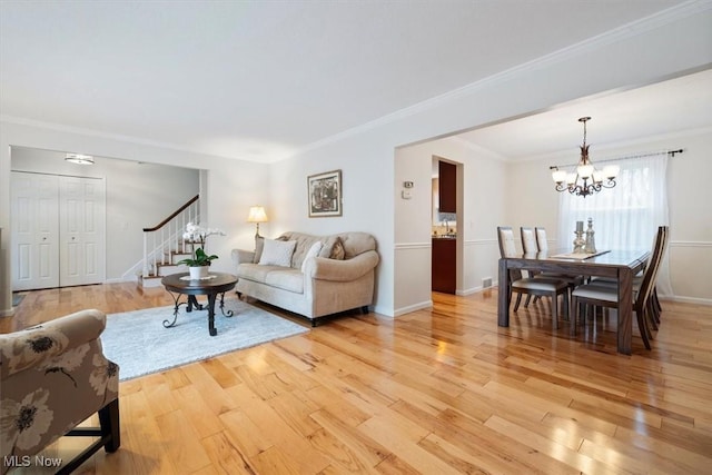 living room with crown molding, light hardwood / wood-style flooring, and a chandelier