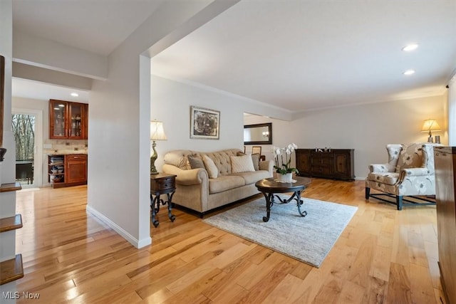 living room with beverage cooler, ornamental molding, and light wood-type flooring