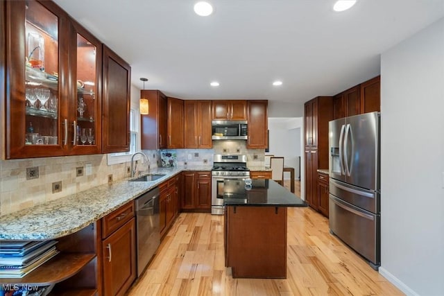 kitchen with hanging light fixtures, sink, a kitchen island, appliances with stainless steel finishes, and light hardwood / wood-style floors