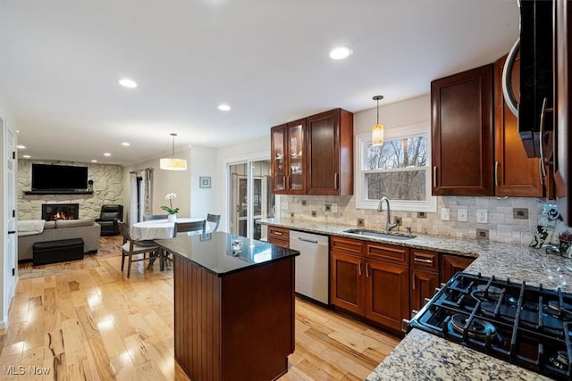 kitchen with light stone countertops, sink, stainless steel appliances, and light hardwood / wood-style floors