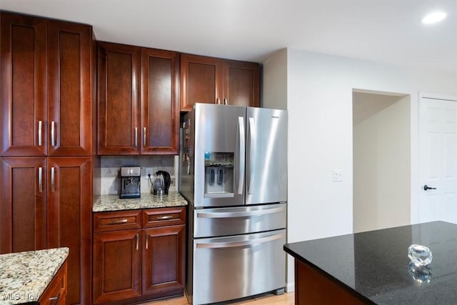 kitchen with tasteful backsplash, stone counters, light hardwood / wood-style flooring, and stainless steel refrigerator with ice dispenser