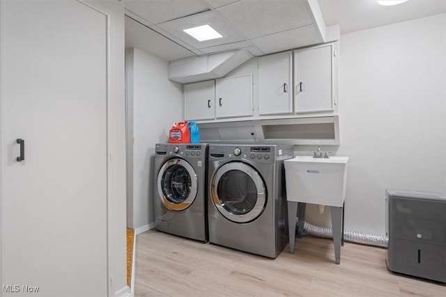 clothes washing area with separate washer and dryer, cabinets, and light wood-type flooring