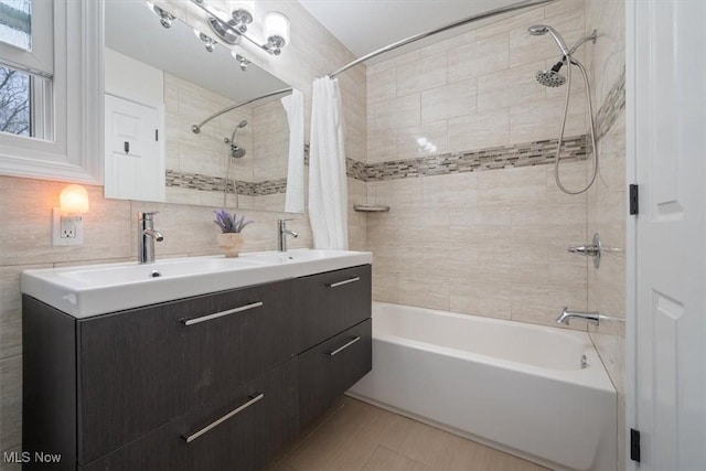 bathroom with backsplash, shower / tub combo with curtain, vanity, and tile walls