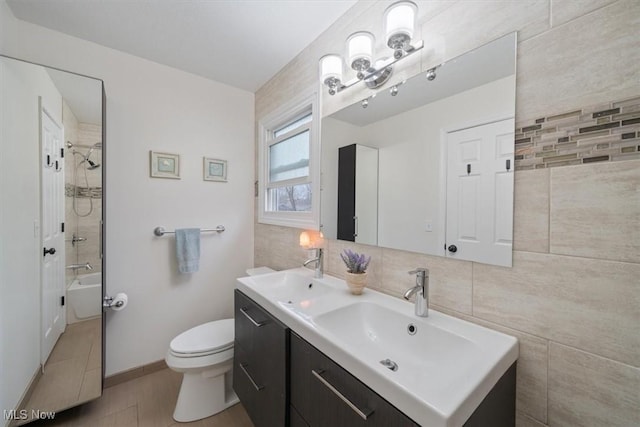 full bathroom featuring toilet, vanity, tile walls, and tiled shower / bath