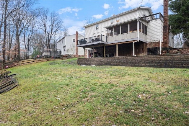 rear view of property with a lawn and a sunroom