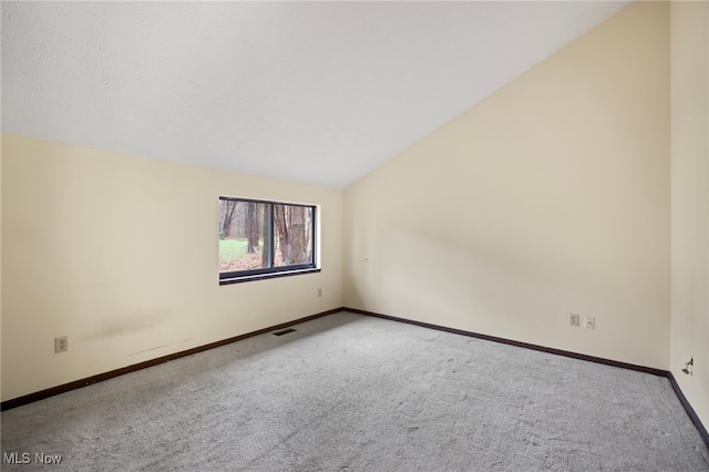 unfurnished room with light colored carpet and lofted ceiling