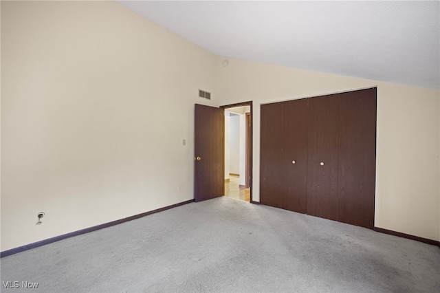 unfurnished bedroom with light colored carpet, high vaulted ceiling, and a closet