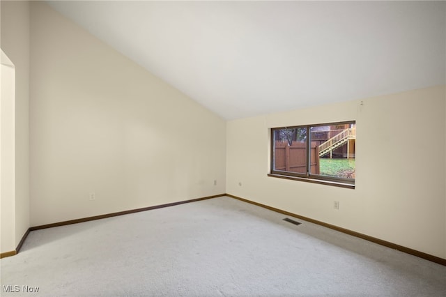 spare room featuring carpet floors and lofted ceiling