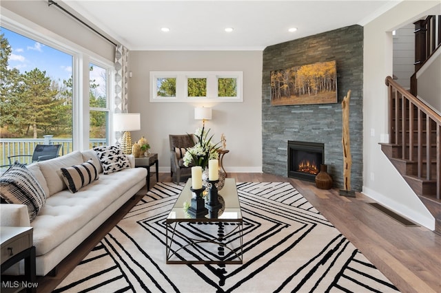 living room featuring crown molding, a fireplace, and light hardwood / wood-style floors