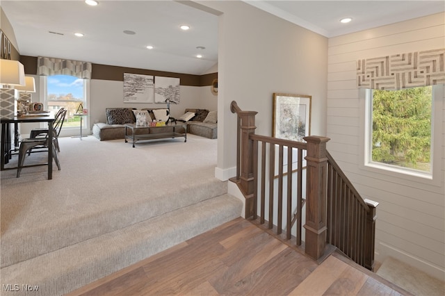 stairway featuring wooden walls, hardwood / wood-style floors, and ornamental molding