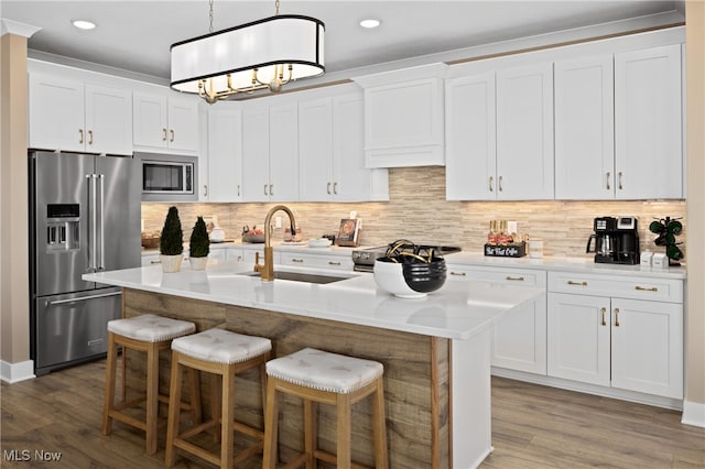 kitchen featuring dark hardwood / wood-style flooring, white cabinetry, stainless steel appliances, and an island with sink