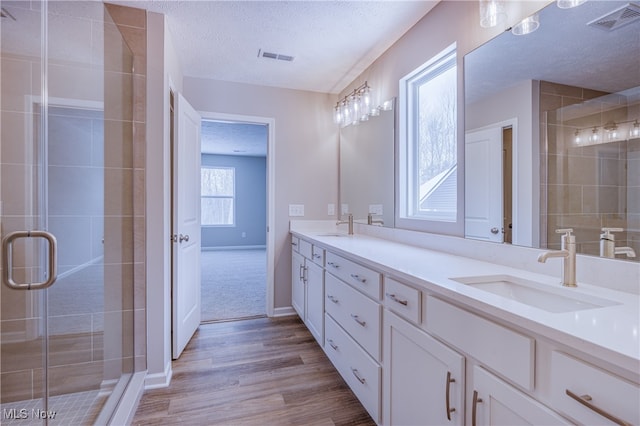 bathroom with a textured ceiling, double vanity, a sink, and visible vents