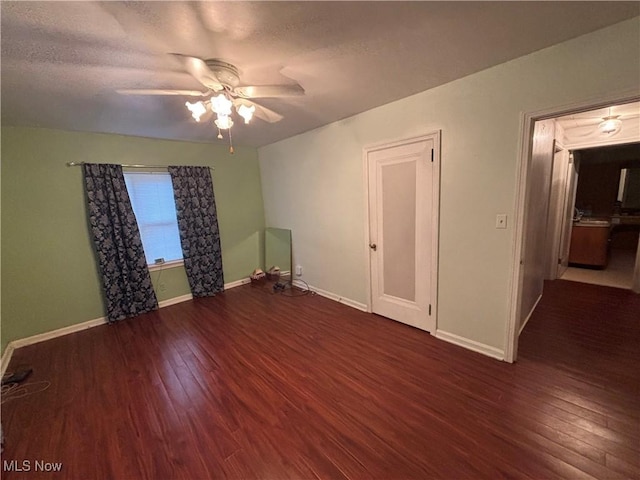 unfurnished room featuring ceiling fan, dark wood-type flooring, and a textured ceiling