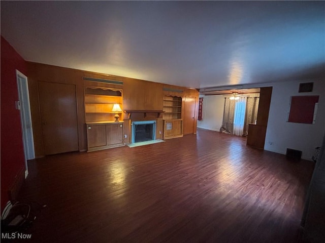 unfurnished living room featuring dark hardwood / wood-style flooring, built in features, and ceiling fan