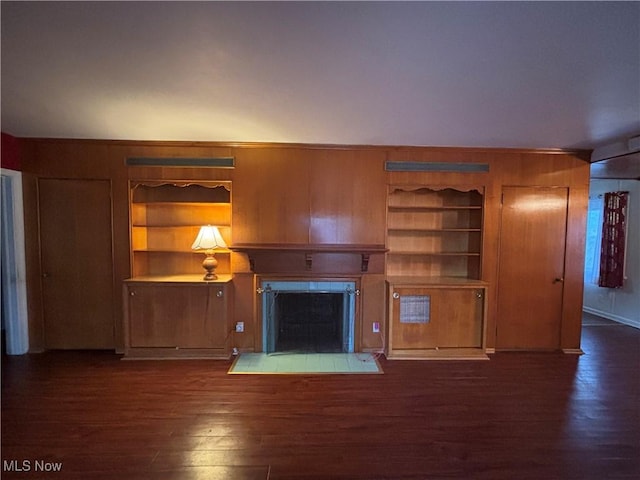 unfurnished living room with wood walls, dark hardwood / wood-style flooring, and built in features