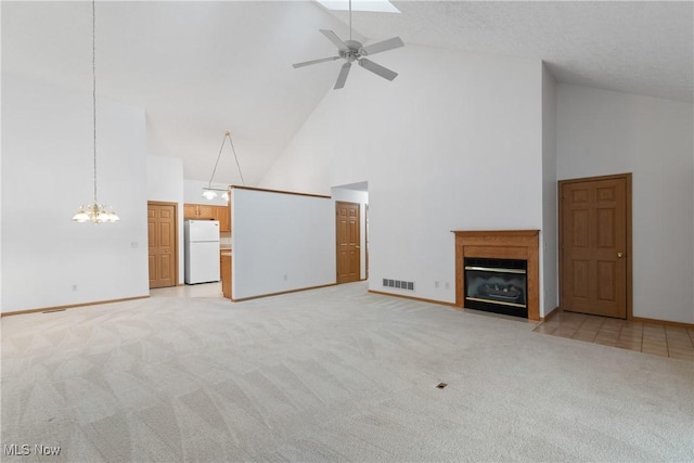 unfurnished living room featuring high vaulted ceiling, light colored carpet, and ceiling fan with notable chandelier