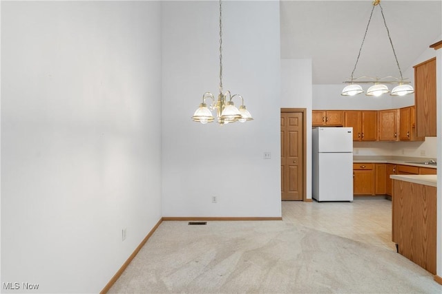 kitchen with high vaulted ceiling, an inviting chandelier, white refrigerator, decorative light fixtures, and light colored carpet