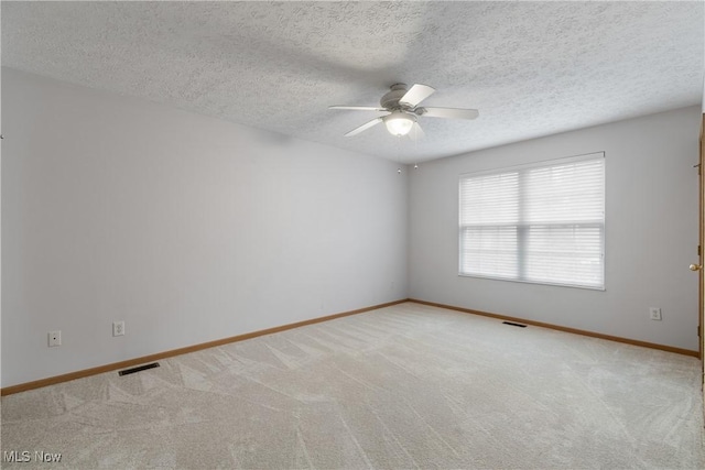 empty room featuring ceiling fan, a textured ceiling, and light carpet